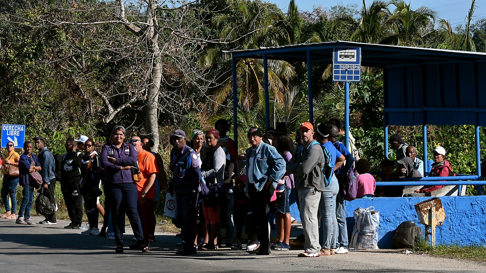 Ryhmä ihmisiä odottaa bussipysäkillä Havannassa. Juna- ja bussivuoroja on harvennettu, ja bensiinin saaminen on päivä päivältä vaikeampaa.